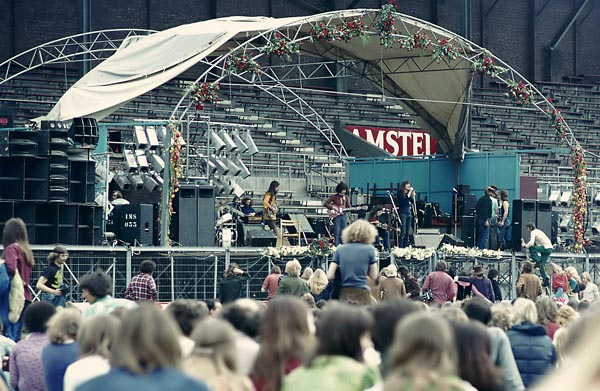1972, 22 mei. Amsterdam, het Olympisch Stadion. Het Amsterdams Rockcircus, met onder anderen Donovan en Pink Floyd. Links de installatie van Pink Floyd. Wij spelen op onze eigen ‘piepkleine’ zaalinstallatie, de 4 grijze boxen, 2 links en 2 rechts van ons. Frits van Doorninck, onze geluidstechnicus, klimt het podium op. Er zal iets mis zijn met het geluid…